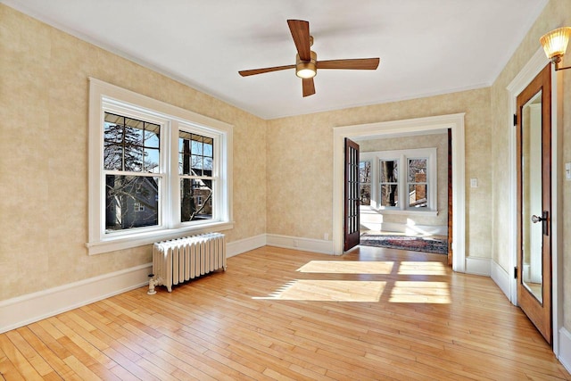 empty room with ceiling fan, radiator, and light hardwood / wood-style flooring