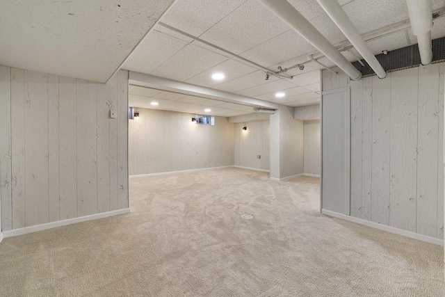 basement with light carpet and wooden walls