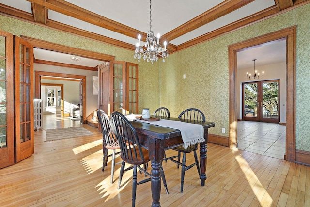 dining area featuring a notable chandelier, light hardwood / wood-style flooring, ornamental molding, and french doors