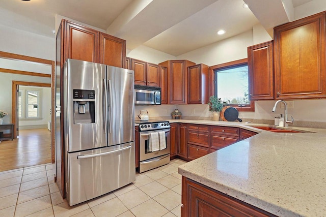 kitchen with light tile patterned flooring, sink, appliances with stainless steel finishes, plenty of natural light, and light stone countertops