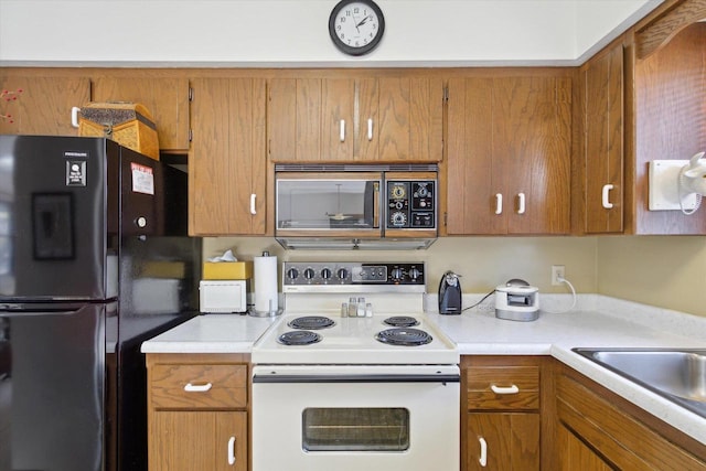 kitchen featuring black refrigerator, sink, and white range with electric cooktop