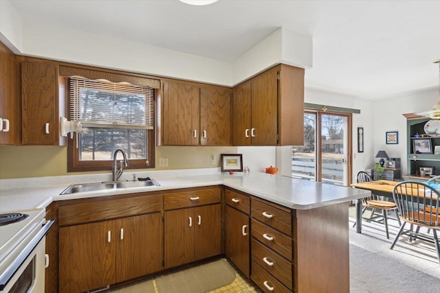 kitchen featuring range with electric cooktop, a healthy amount of sunlight, kitchen peninsula, and sink