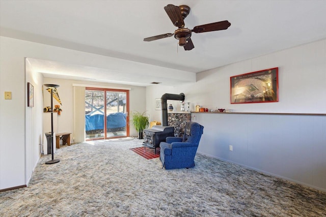 living area with a wood stove, ceiling fan, and carpet