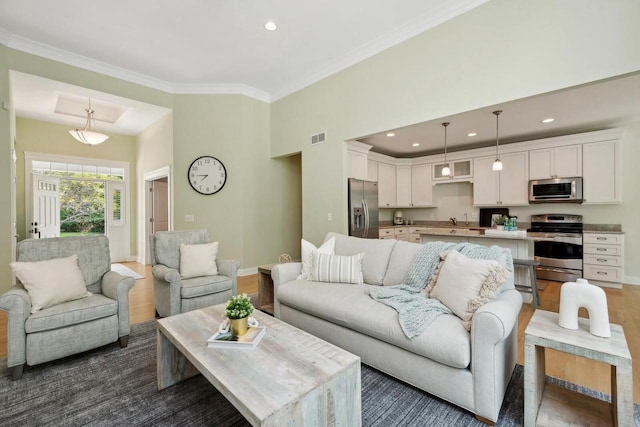 living room featuring dark wood-type flooring, a towering ceiling, ornamental molding, and sink