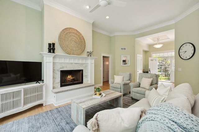 living room with ornamental molding, a premium fireplace, and light wood-type flooring