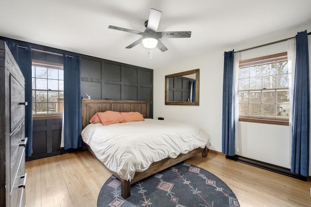 bedroom featuring multiple windows, ceiling fan, and light wood-type flooring