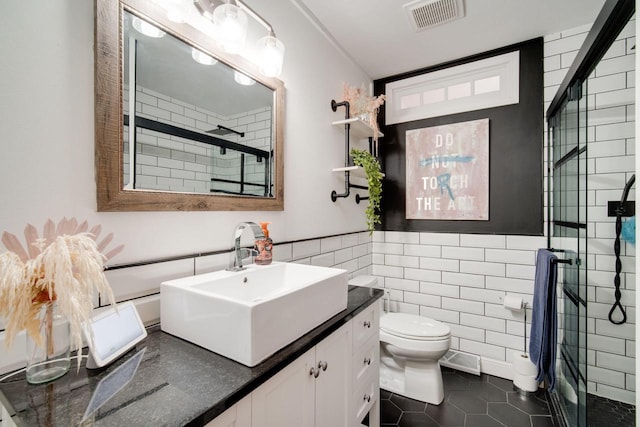 bathroom featuring a shower with shower door, tile walls, tile patterned flooring, vanity, and toilet