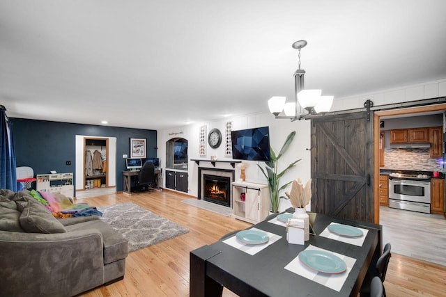 living room featuring light hardwood / wood-style flooring, a barn door, and a chandelier