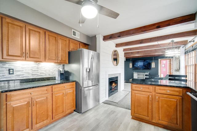 kitchen featuring stainless steel fridge, dark stone countertops, beam ceiling, light hardwood / wood-style floors, and decorative backsplash