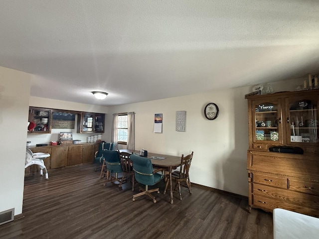 dining room with dark wood-type flooring and a textured ceiling