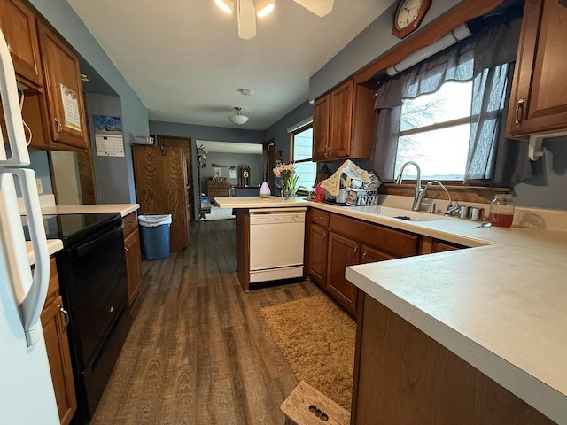 kitchen with sink, ceiling fan, kitchen peninsula, dark wood-type flooring, and white appliances