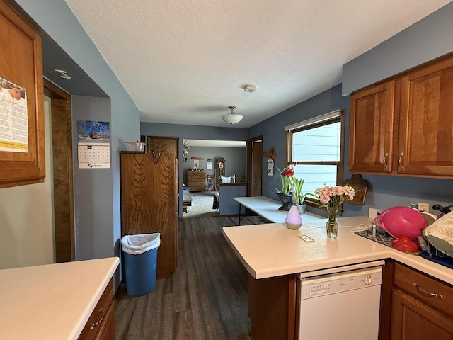 kitchen with dishwasher, dark hardwood / wood-style flooring, a textured ceiling, and kitchen peninsula