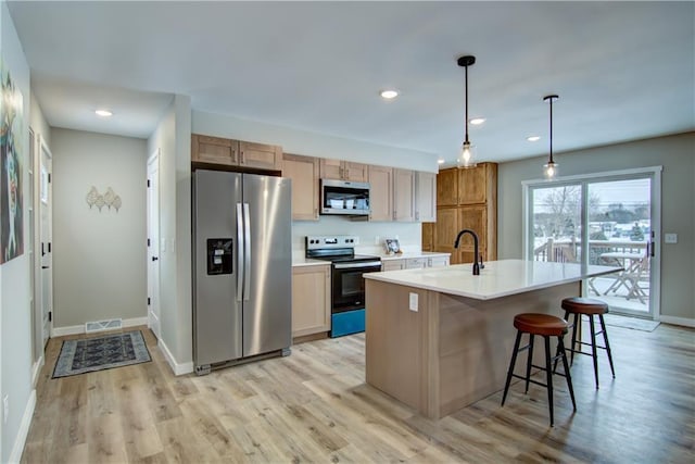 kitchen with pendant lighting, sink, a breakfast bar area, appliances with stainless steel finishes, and an island with sink