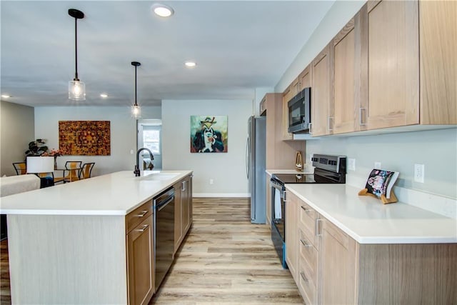 kitchen featuring sink, appliances with stainless steel finishes, a kitchen island with sink, decorative light fixtures, and light brown cabinets