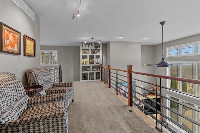 living area featuring ceiling fan, a healthy amount of sunlight, rail lighting, and light carpet