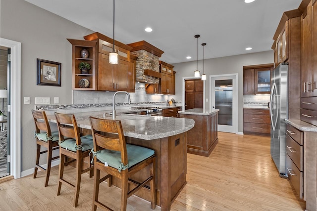 kitchen with a kitchen breakfast bar, a center island, stainless steel appliances, light stone countertops, and decorative light fixtures