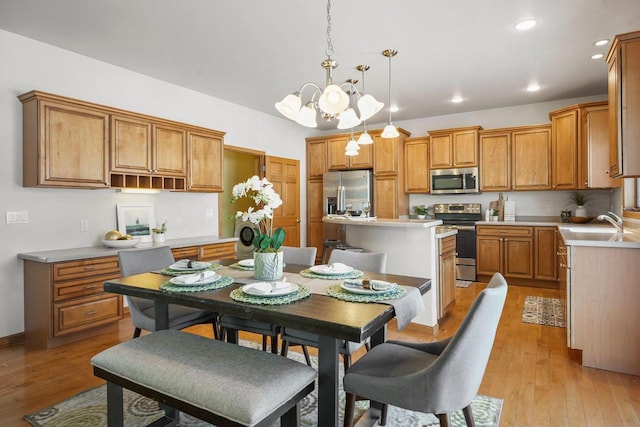 kitchen with decorative light fixtures, sink, a center island, light hardwood / wood-style floors, and stainless steel appliances