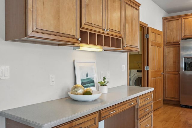 kitchen featuring washer / dryer, light wood-type flooring, and stainless steel refrigerator with ice dispenser