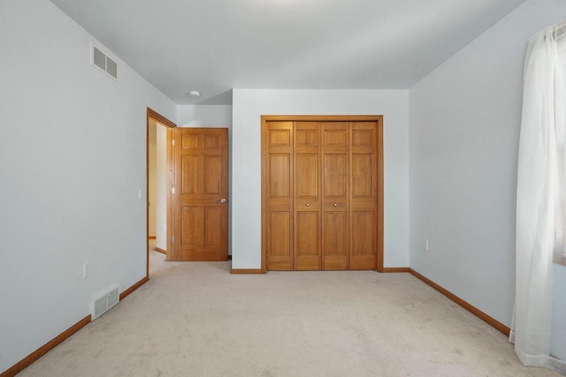 unfurnished bedroom featuring light carpet and a closet