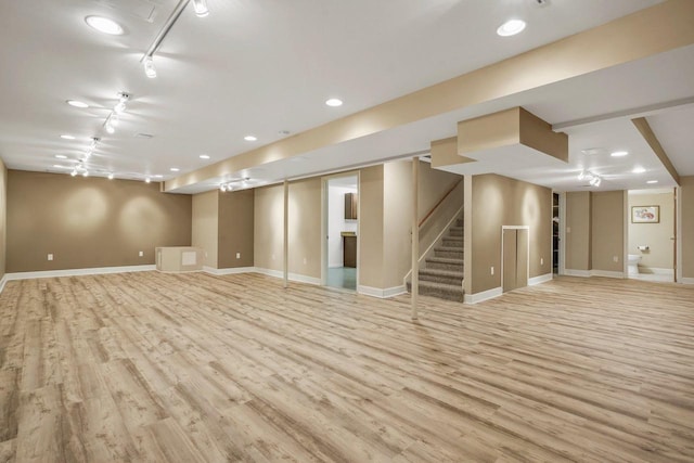 basement featuring track lighting and light wood-type flooring