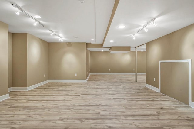 basement featuring track lighting and light wood-type flooring