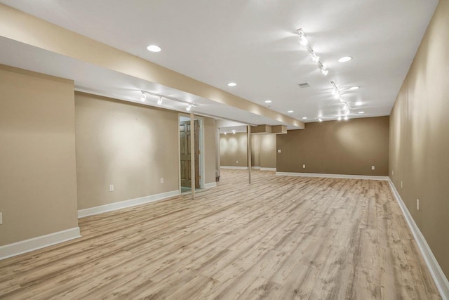 basement with track lighting and light hardwood / wood-style floors