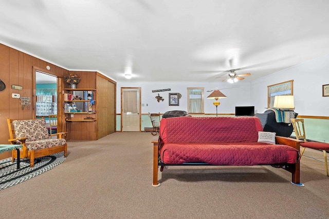 carpeted living room with wooden walls and ceiling fan