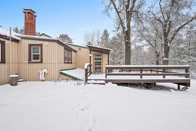 snow covered rear of property with a wooden deck