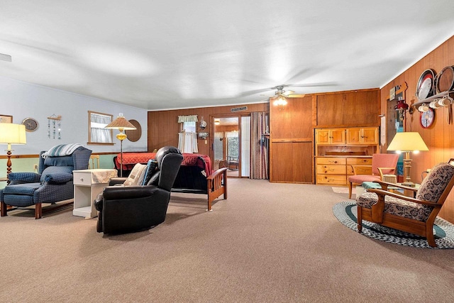 living room featuring ceiling fan, light colored carpet, and wood walls