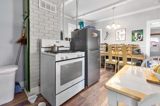 kitchen featuring an inviting chandelier, hanging light fixtures, stainless steel refrigerator, dark hardwood / wood-style floors, and white gas range