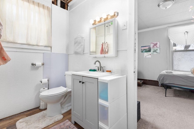 bathroom with hardwood / wood-style floors, vanity, tile walls, and toilet