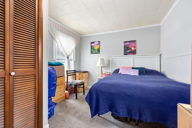 bedroom with a closet, ornamental molding, and carpet