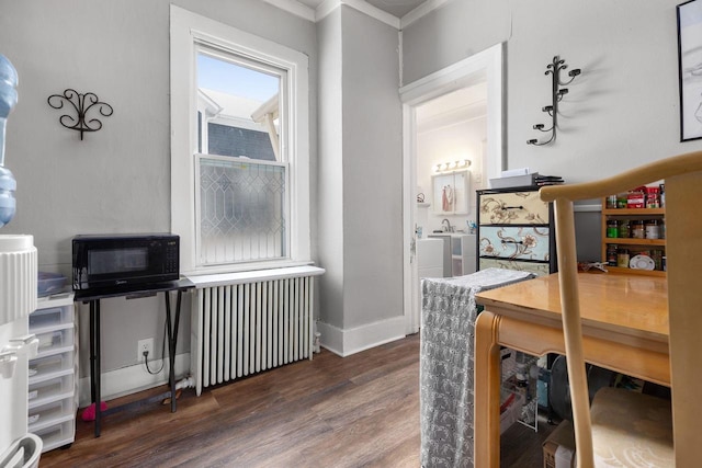 home office with dark hardwood / wood-style flooring, sink, crown molding, and radiator heating unit