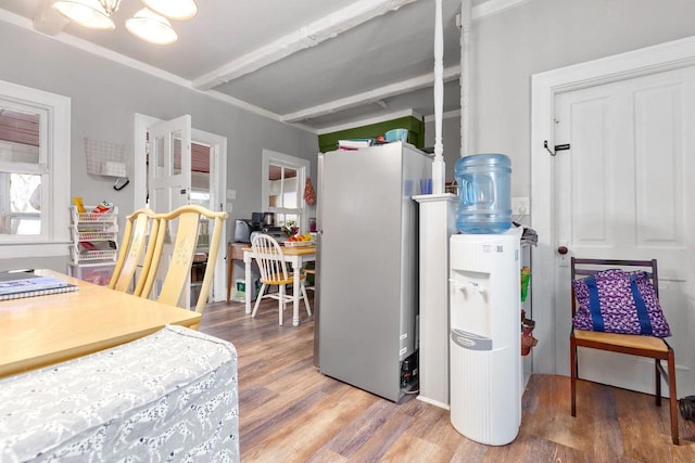 kitchen featuring beam ceiling, stainless steel fridge, a chandelier, and wood-type flooring