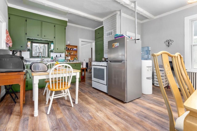 kitchen with white gas range oven, stainless steel refrigerator, green cabinets, hardwood / wood-style floors, and ornamental molding