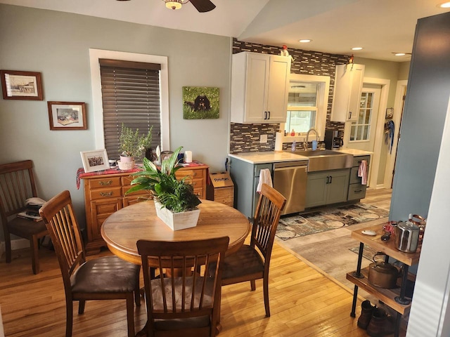 dining space with vaulted ceiling, ceiling fan, sink, and light hardwood / wood-style flooring