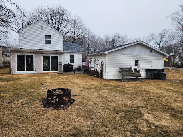 rear view of house with a yard and an outdoor fire pit