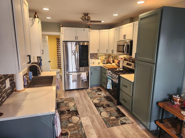 kitchen featuring sink, white cabinetry, stainless steel appliances, tasteful backsplash, and light hardwood / wood-style floors