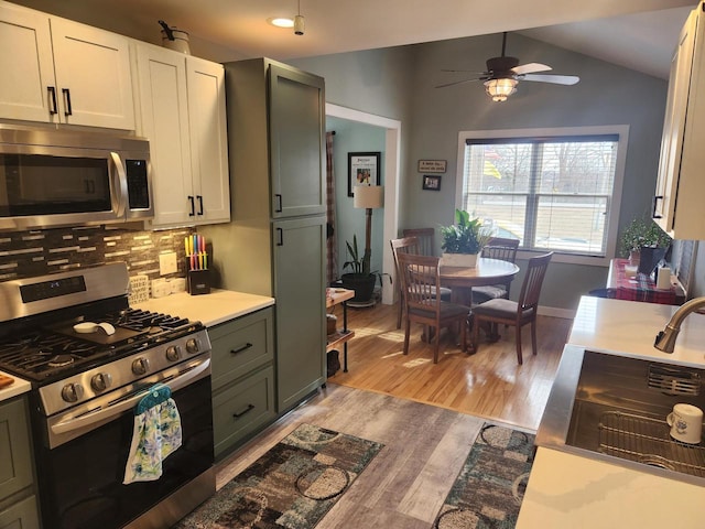 kitchen featuring stainless steel appliances, gray cabinets, vaulted ceiling, and light hardwood / wood-style flooring