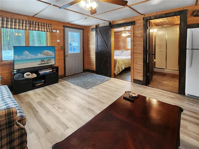 living room with light hardwood / wood-style flooring, a barn door, and wood walls