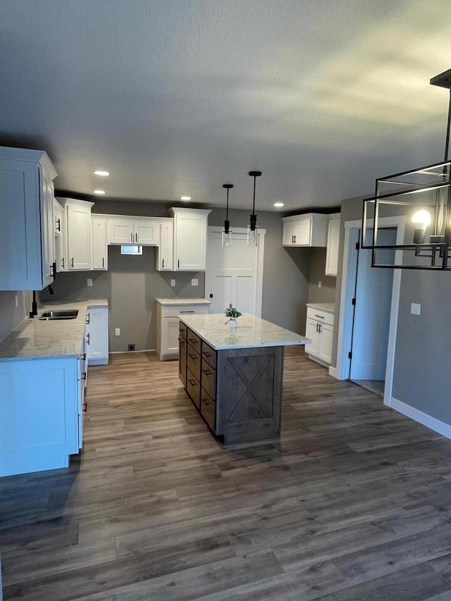 kitchen featuring dark wood-type flooring, a kitchen island, hanging light fixtures, and white cabinets