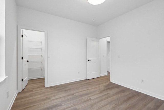 unfurnished bedroom featuring a walk in closet and light wood-type flooring