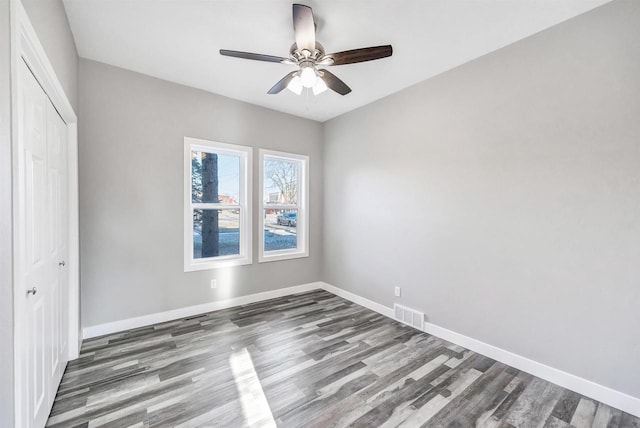 unfurnished bedroom with dark hardwood / wood-style floors, a closet, and ceiling fan