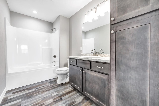 full bathroom featuring wood-type flooring, toilet, bathing tub / shower combination, and vanity