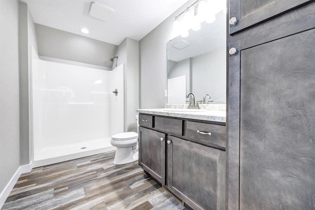 bathroom featuring vanity, hardwood / wood-style flooring, a shower, and toilet