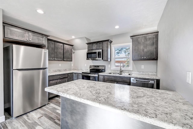 kitchen with dark brown cabinetry, sink, light hardwood / wood-style floors, and appliances with stainless steel finishes