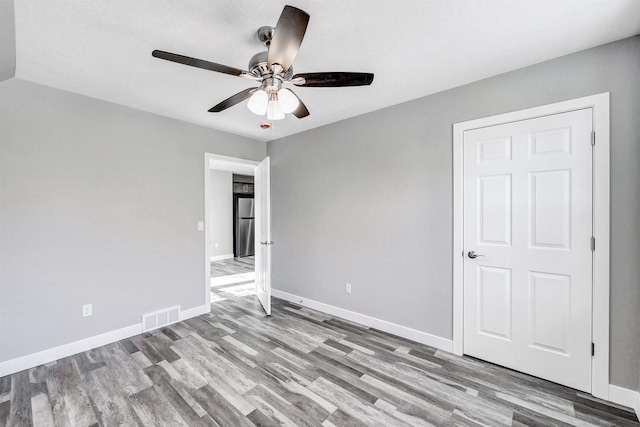 unfurnished bedroom featuring stainless steel fridge, ceiling fan, and light hardwood / wood-style flooring