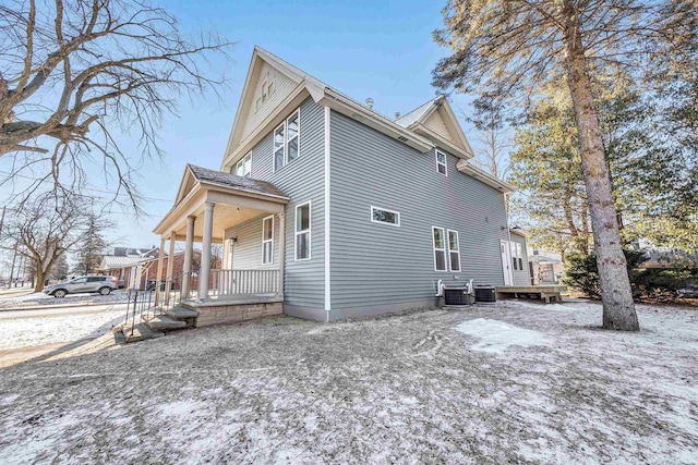 view of snow covered exterior with a porch and central AC unit