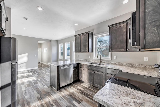 kitchen with sink, dark brown cabinets, stainless steel appliances, dark hardwood / wood-style floors, and kitchen peninsula