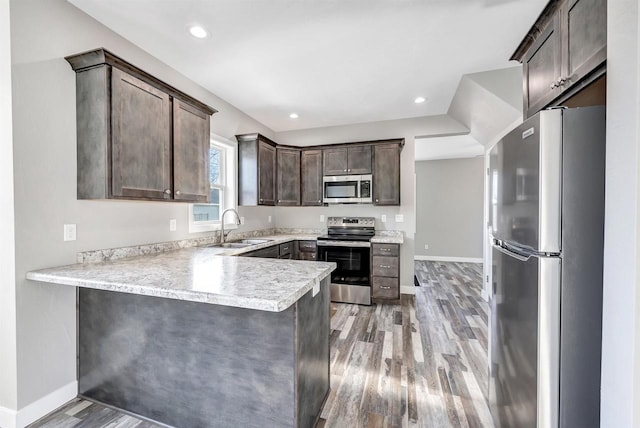 kitchen featuring sink, dark brown cabinets, light wood-type flooring, kitchen peninsula, and stainless steel appliances